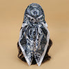 A patterned blue and white satin square scarf tied around dark hair.