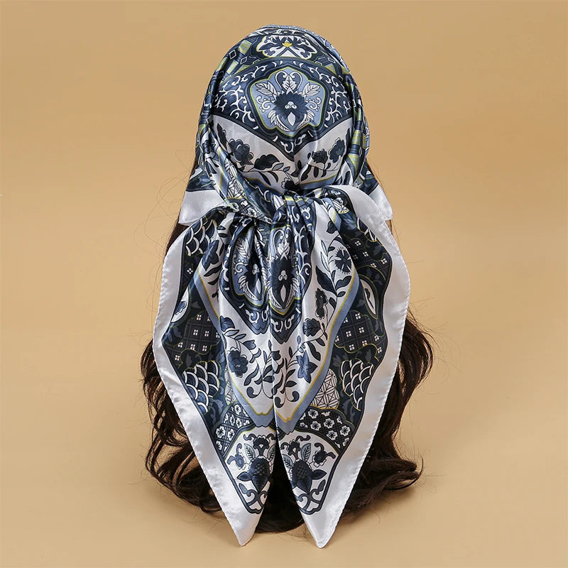 A patterned blue and white satin square scarf tied around dark hair.