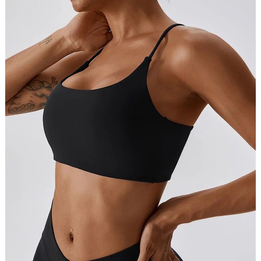 Una mujer vistiendo un sujetador deportivo en forma de U negro para fitness y yoga.