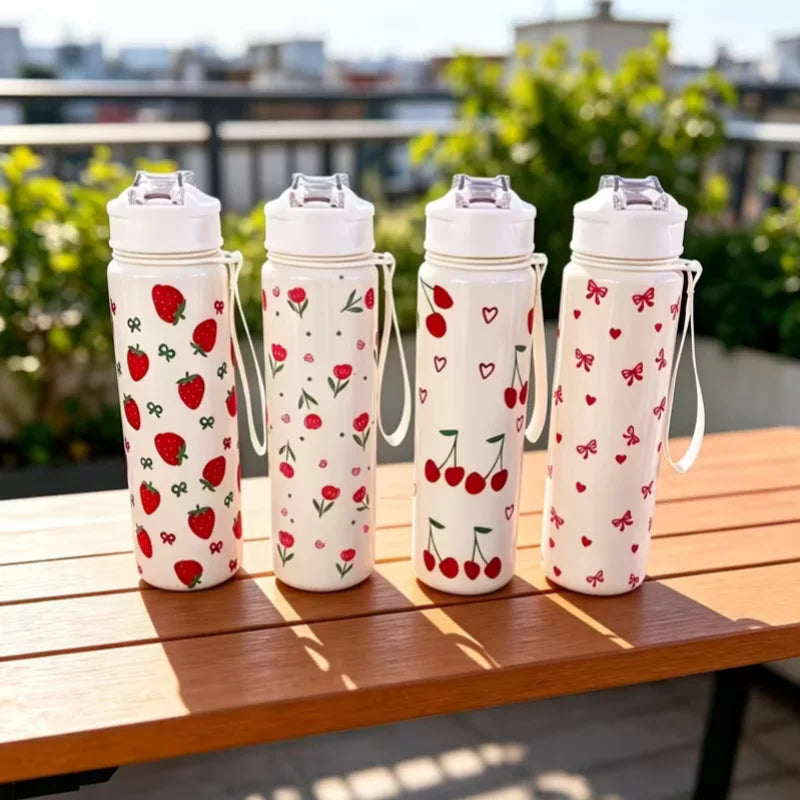 Four white tumblers decorated with red strawberries, cherries, and small flowers sitting on a wooden table.