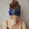 A close-up of a person wearing a navy blue patterned boho headband tied around their head.