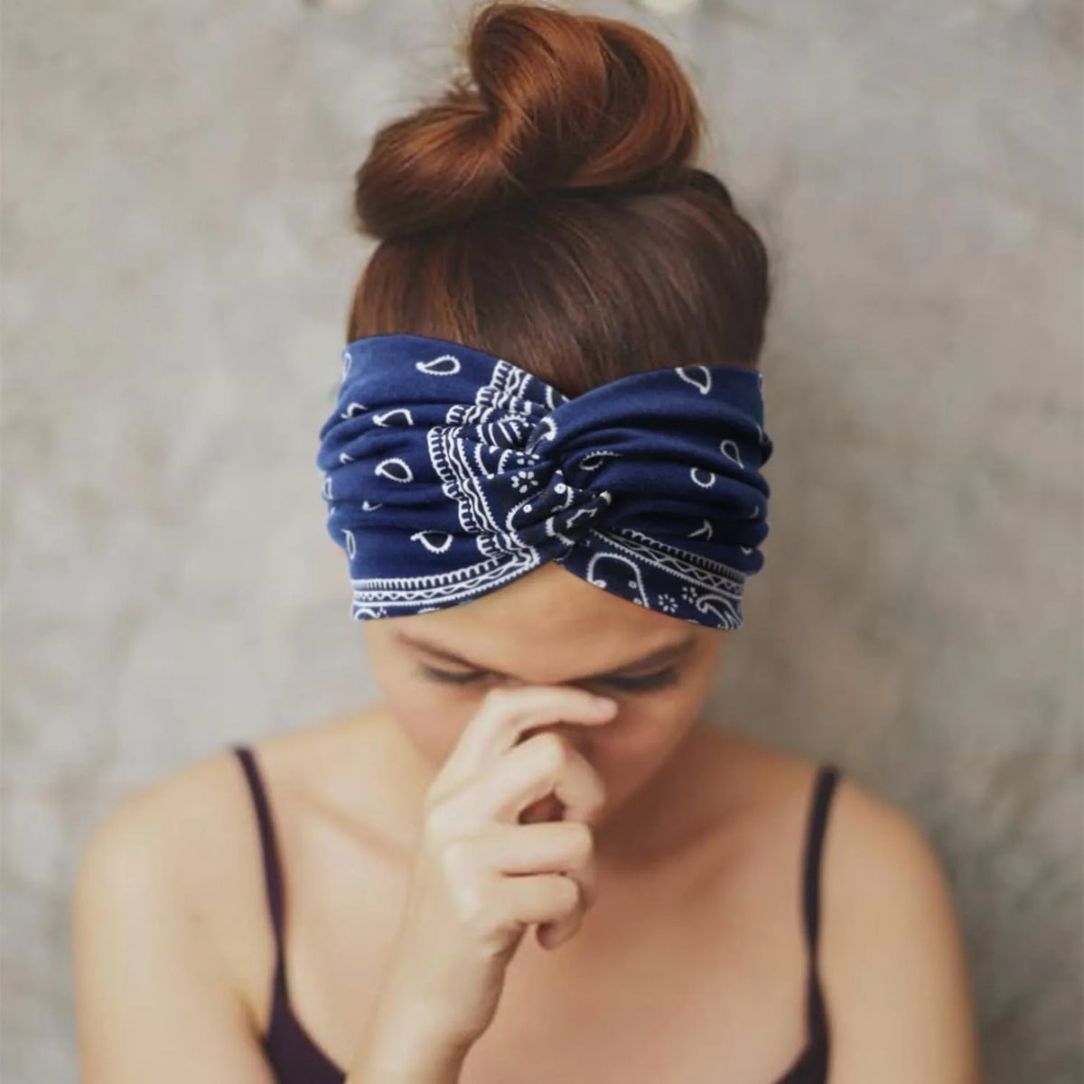 A close-up of a person wearing a navy blue patterned boho headband tied around their head.