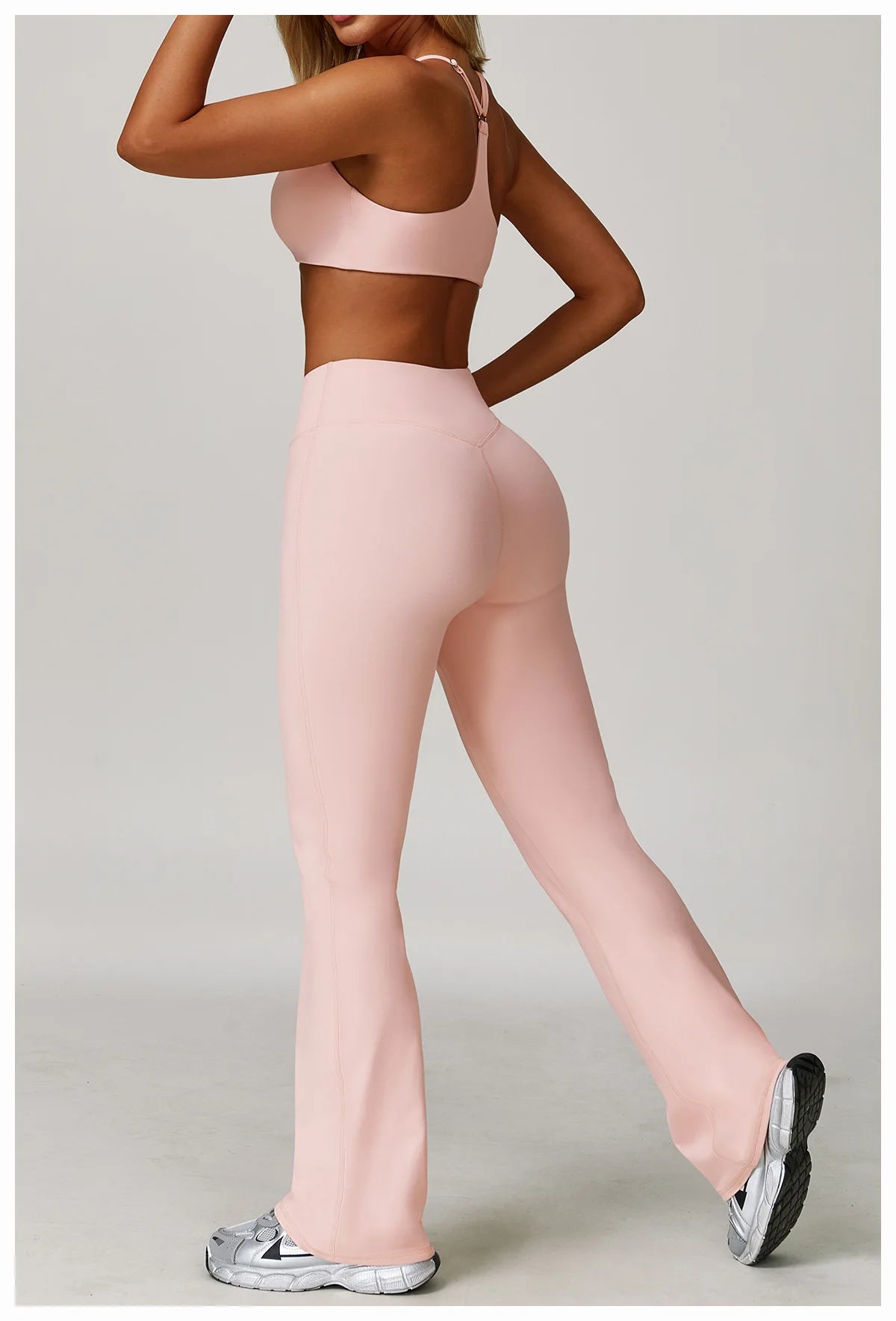 A woman models a pink 3-piece yoga sports set consisting of a crop top, leggings, and matching pants.