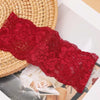 Primer plano de una diadema de encaje floral roja vibrante sobre una estera tejida junto a ropa.