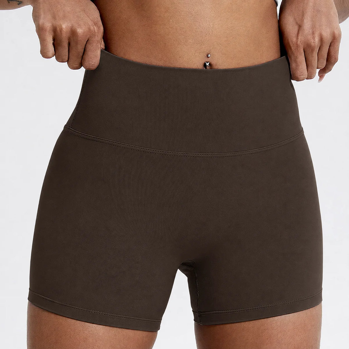Un mannequin porte des shorts de yoga et de sport à taille haute en compression de couleur marron foncé.
