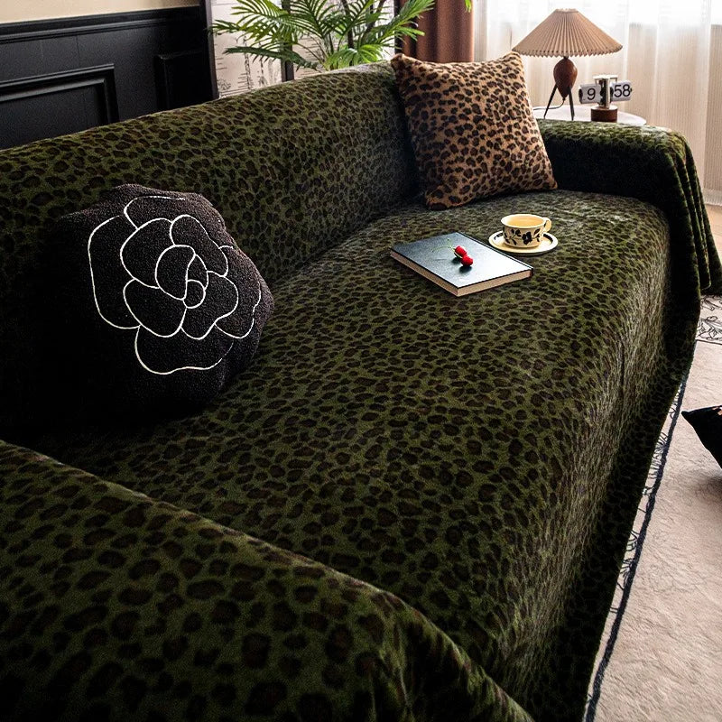 A dark green plush sofa cover blanket with a leopard print pattern, featuring decorative pillows and a small tray.