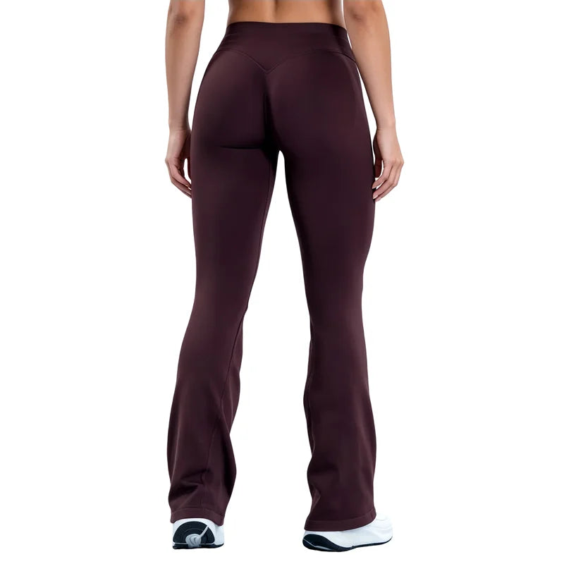 A model wearing dark plum seamless flared yoga leggings and white athletic shoes.