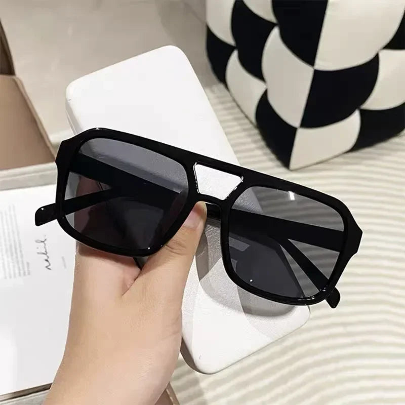 Un par de gafas de sol cuadradas negras sobre una superficie blanca.