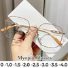 A hand holds a pair of thin, wire-framed reading glasses with light brown frames and white temples against a white background