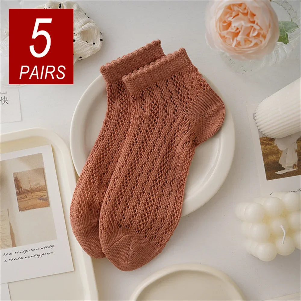Five pairs of knitted, breathable mesh lace tube socks in a dusty rose color displayed on a white plate.