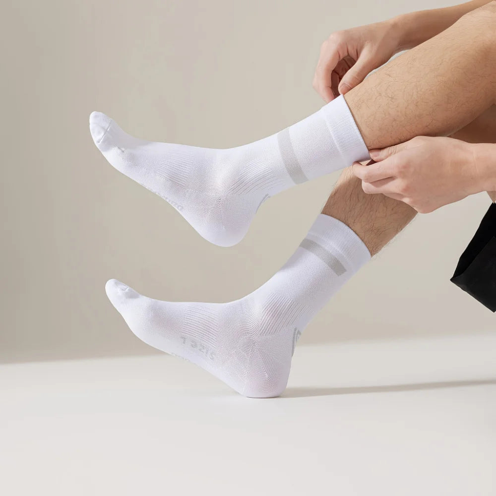 A person is putting on white performance athletic running socks on their foot and ankle.