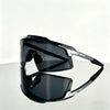 A pair of black TR90 UV400 sports sunglasses resting on a reflective surface.