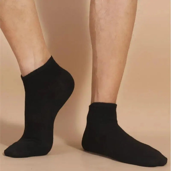 A pair of black breathable unisex boat socks worn on a person's feet.