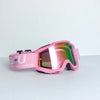 Pink sport-grade skiing goggles with a pink strap and mirrored lenses resting on a white surface.