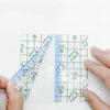 A transparent sheet of invisible leg lifting patches is shown being held by a hand.