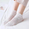 Pair of sheer white lace mesh ankle socks worn by a person, displayed on a white surface.
