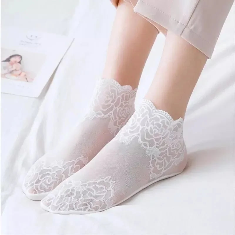Pair of sheer white lace mesh ankle socks worn by a person, displayed on a white surface.