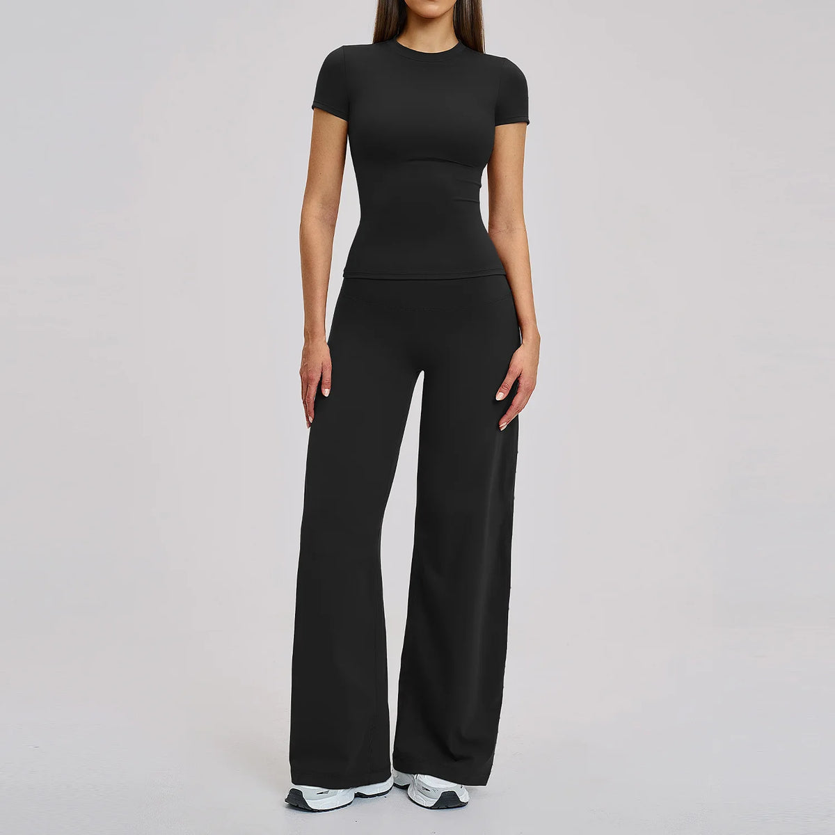 A woman wearing a black women's premium fitness tracksuit top and matching pants.