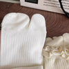 White knit crew socks with ruffled cuffs shown on a wooden surface.