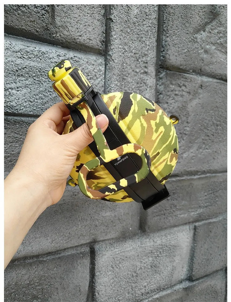 A hand holds a yellow and green patterned silicone camping kettle against a gray brick wall.