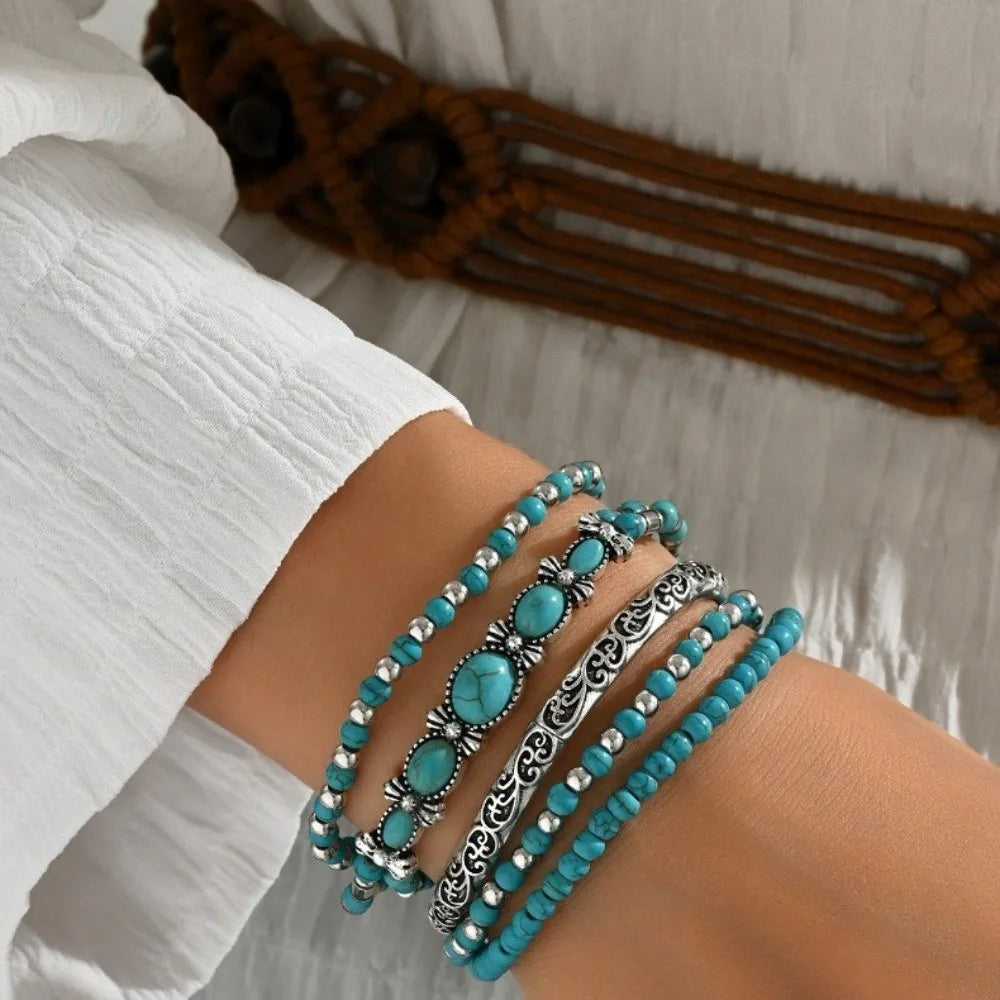 Gros plan d'une main portant cinq bracelets de perles turquoise au poignet.