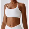 Modelo vistiendo un sujetador deportivo en forma de U blanco y la parte inferior a juego para fitness o yoga.