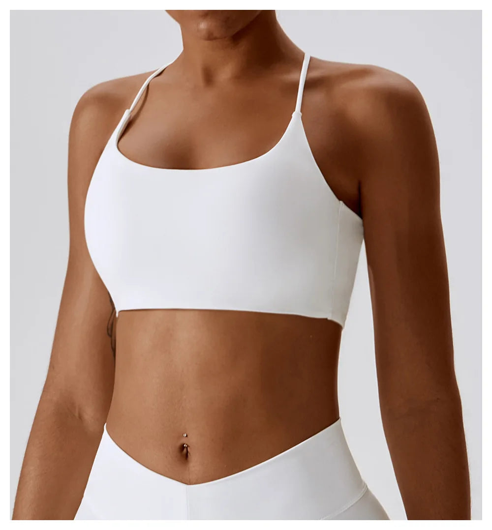 Modelo vistiendo un sujetador deportivo en forma de U blanco y la parte inferior a juego para fitness o yoga.