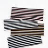 Un paquete de cuatro bandas elásticas para el cabello a rayas en tonos negro, blanco y rosa.