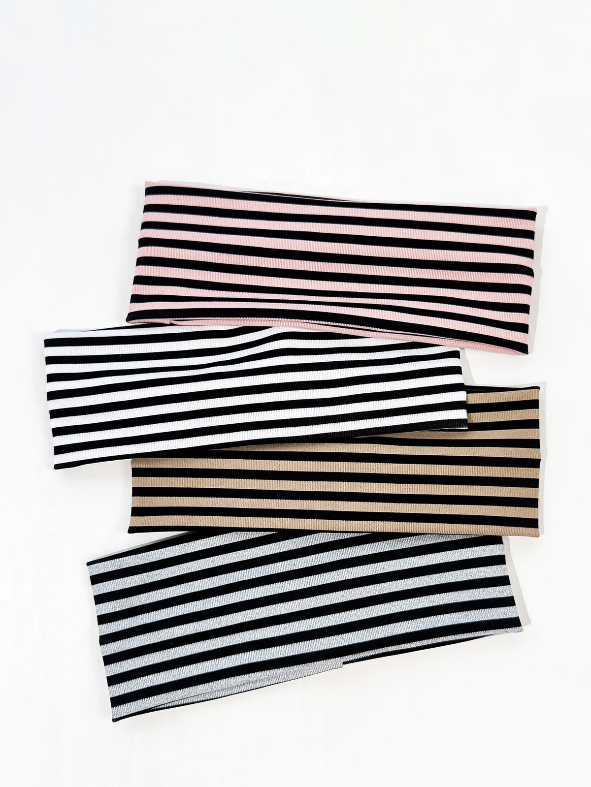 Un paquete de cuatro bandas elásticas para el cabello a rayas en tonos negro, blanco y rosa.