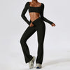 A woman wearing a black performance tracksuit set consisting of a cropped top and matching trousers.
