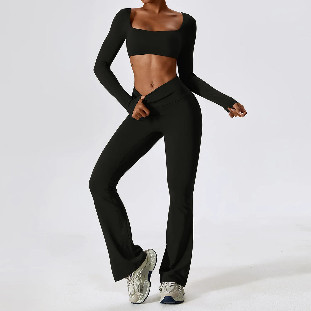 A woman wearing a black performance tracksuit set consisting of a cropped top and matching trousers.
