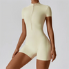 A model wearing a cream-colored seamless yoga jumpsuit with a high collar and zippered front.