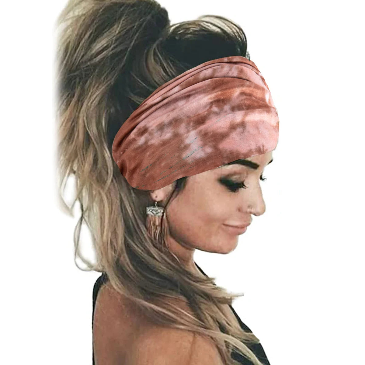 Una mujer vistiendo un pañuelo de estilo bohemio tie-dye color rosa polvoriento recogido en una coleta alta.