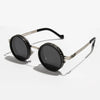 A pair of black round sunglasses with silver metal frames and adjustable dimming.