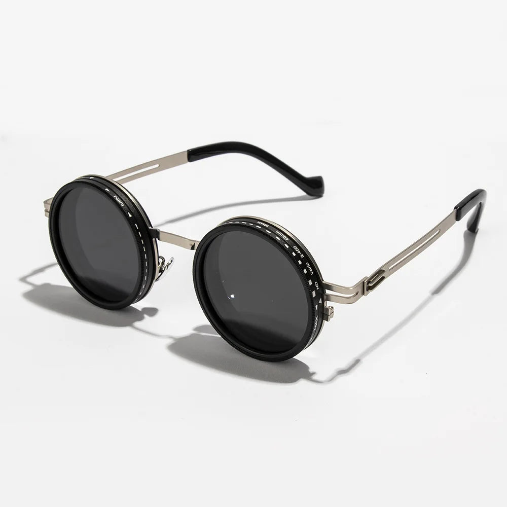 A pair of black round sunglasses with silver metal frames and adjustable dimming.
