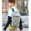 A young man wearing a white shirt and black sleeves is carrying a gray hiking backpack outdoors.