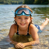 A smiling young girl wearing blue swimming goggles in clear water