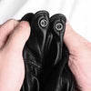 A hand is holding a pair of black leather motorcycle riding gloves.