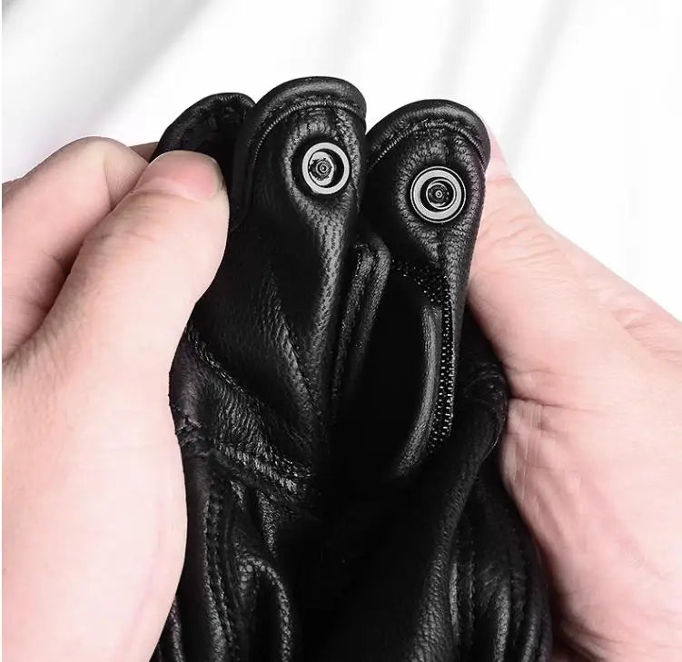 A hand is holding a pair of black leather motorcycle riding gloves.