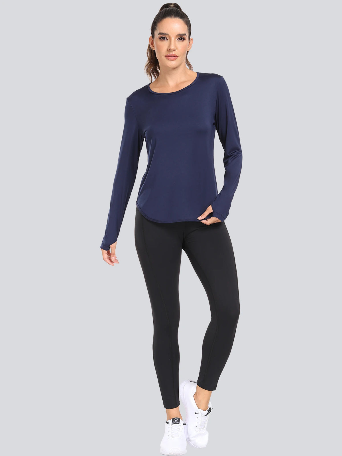 A woman models a navy blue loose fit sun protection t-shirt and black leggings.