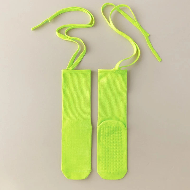 A pair of neon yellow silicone anti-slip yoga socks with elastic drawstrings.