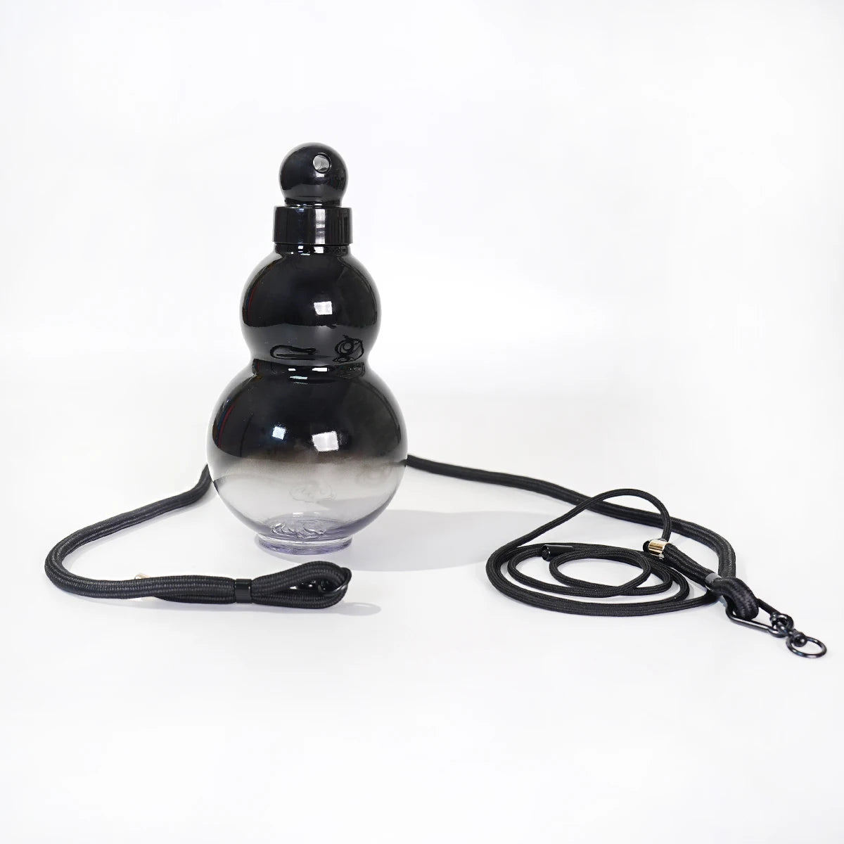 Schwarze, kürbisförmige Sportflasche mit klarem Glas und schwarzem Trageriemen.
