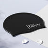 Gorra de natación de silicona negra con la palabra Happy escrita en cursiva blanca sobre un fondo claro.