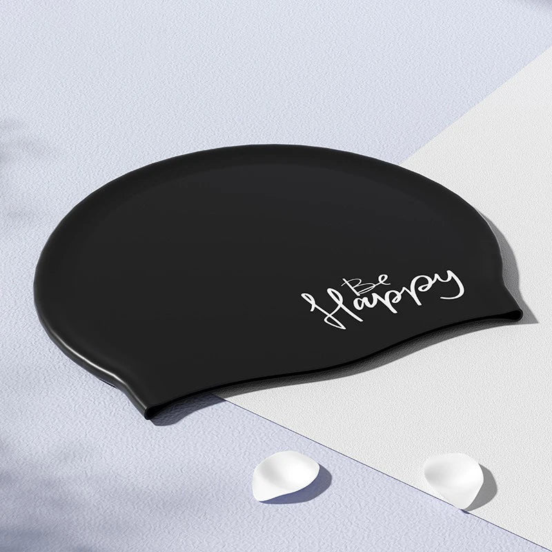 Gorra de natación de silicona negra con la palabra Happy escrita en cursiva blanca sobre un fondo claro.