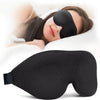 A black light blocking sleep mask is shown being worn by a woman resting on a white pillow.