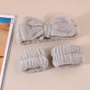 A set of gray microfiber spa headband and wristband featuring a large bow design.