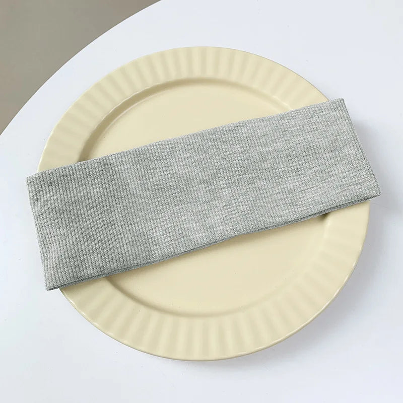 A stack of five gray elastic hairbands resting on a light beige plate.