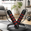 A pair of black and red adjustable weighted speed jump ropes lying on a black mat.