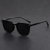 Black square sunglasses with thin arms resting on a dark surface.