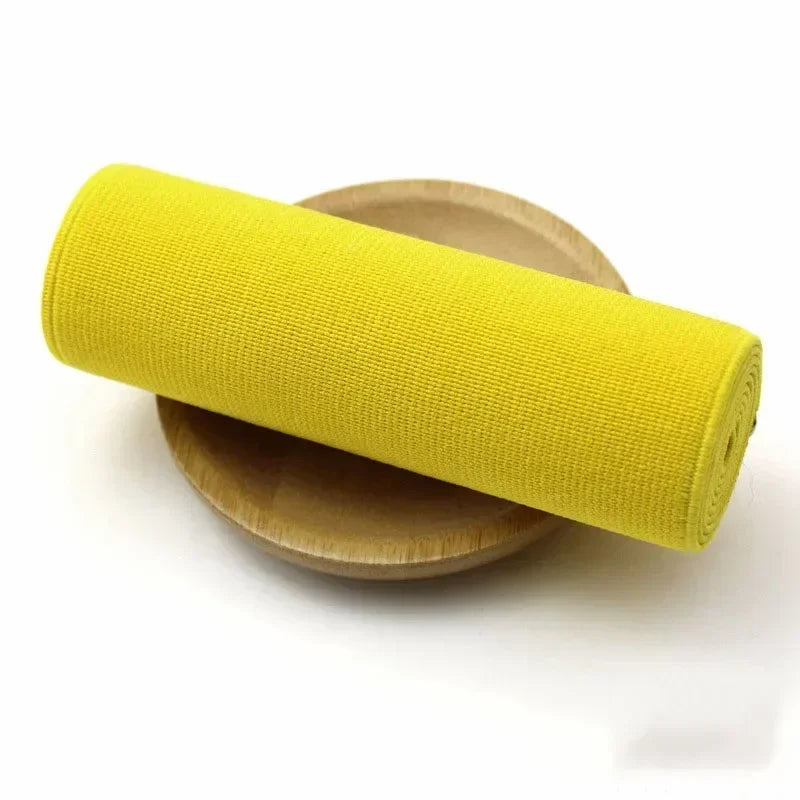 A bright yellow elastic band rolled up, resting on a wooden surface.